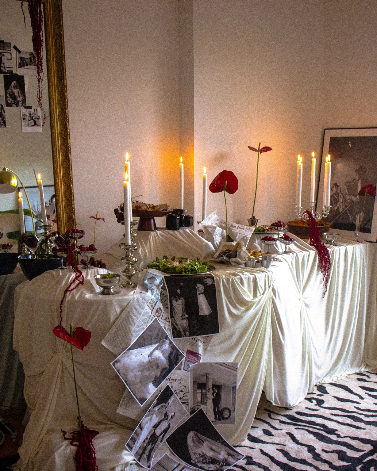 Art de la table éditorial avec drapés ivoire, bougeoirs argentés et fleurs rouges
