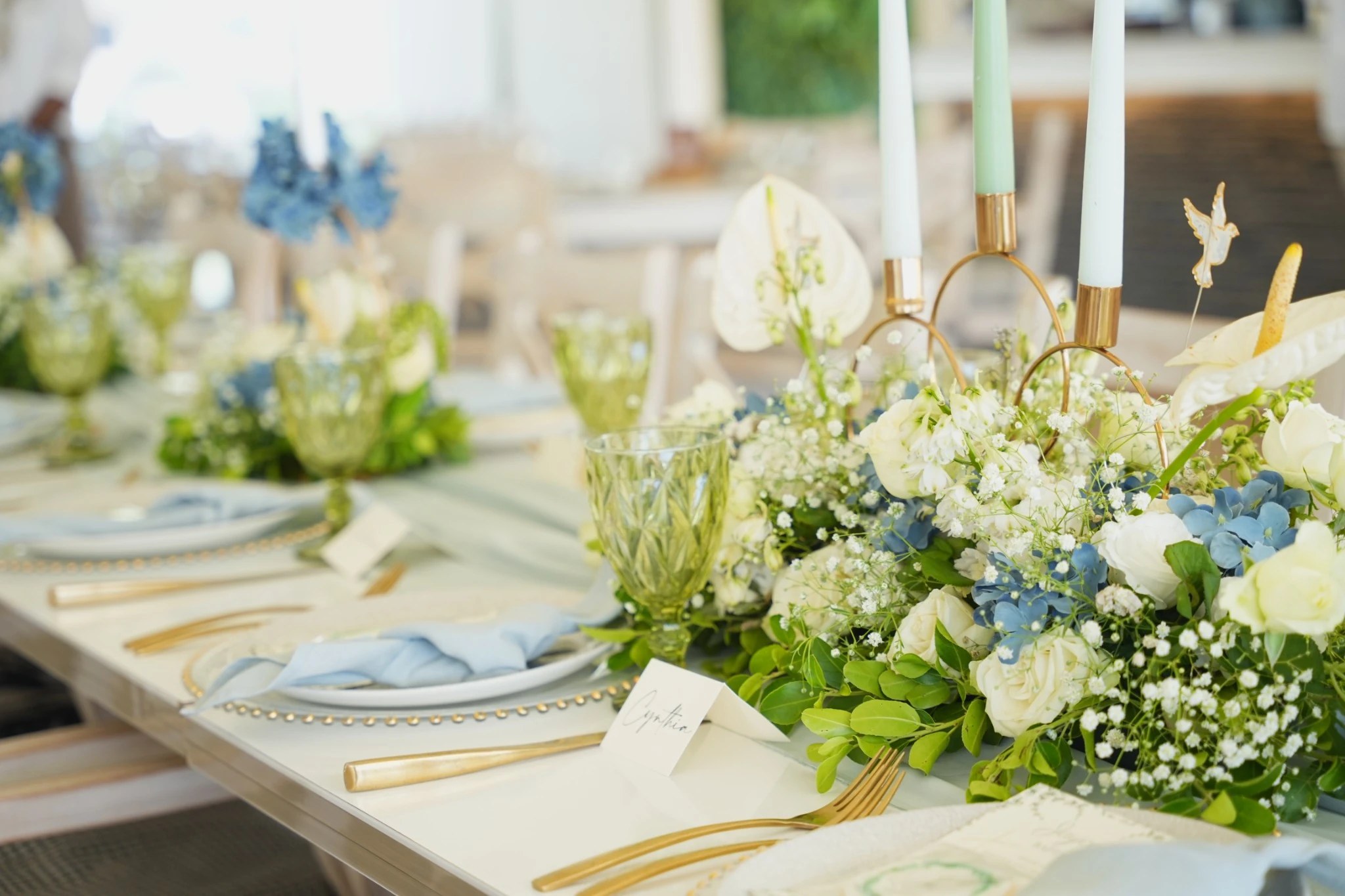 Détails de table : hortensias bleus, bougies et couverts dorés